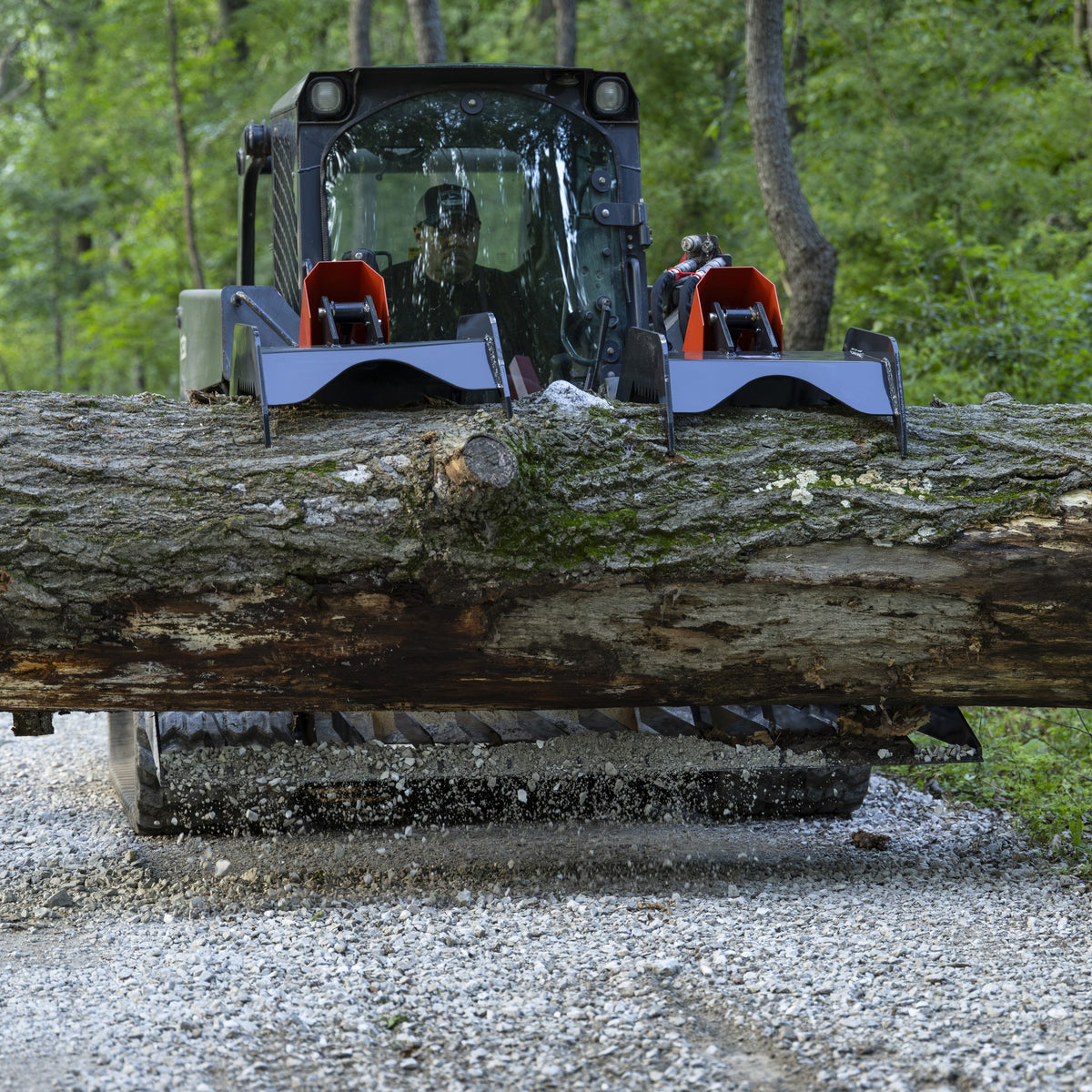 Skid steer carrying a log with rock grapple
